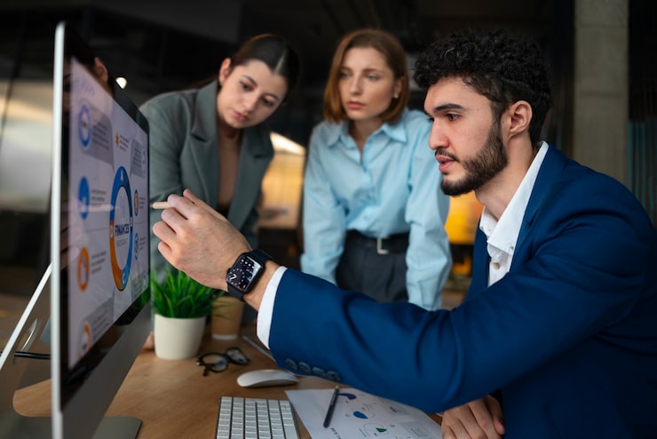 A person pointing at a financial dashboard on a screen, discussing analytics and cost-effective growth strategies with his colleagues